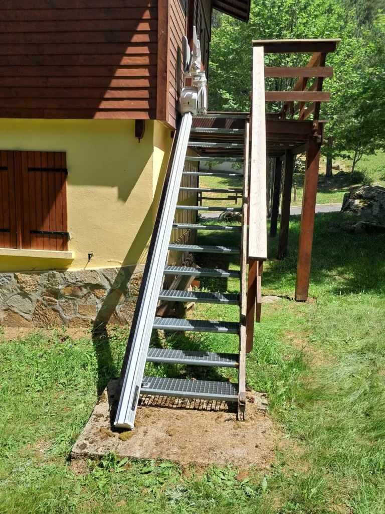 photo de l'escalier avec le rail et la chaise monte-escaliers en haut vue de face