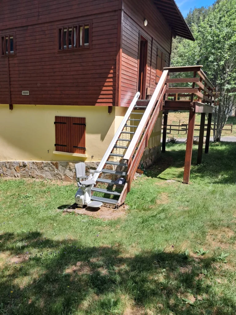 photo de l'escalier et du fauteuil vue de loin avec la chaise en bas du rail